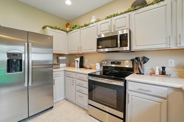 kitchen with stainless steel appliances, light tile patterned floors, light countertops, white cabinetry, and recessed lighting