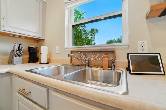 kitchen view of a sink, white cabinets, and light countertops
