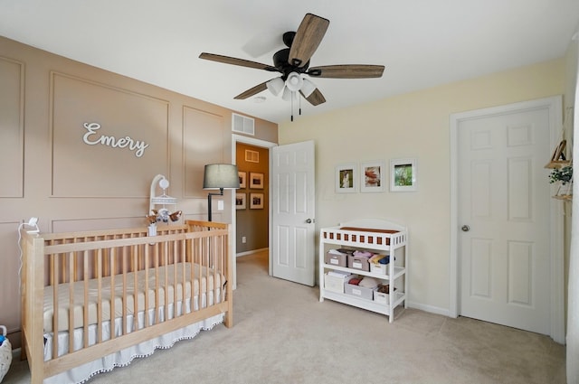bedroom with carpet flooring, a nursery area, baseboards, and ceiling fan