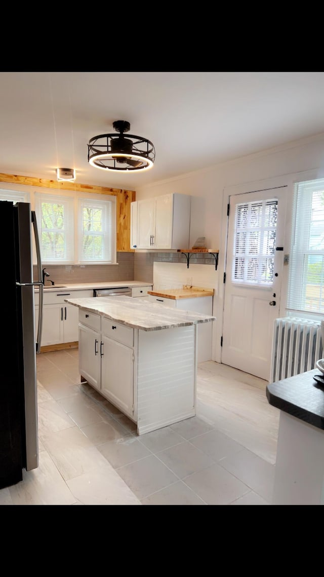 1065 Sunbury Rd, Columbus, OH 43219 - kitchen featuring freestanding refrigerator, radiator heating unit, healthy amount of natural light, and a center island