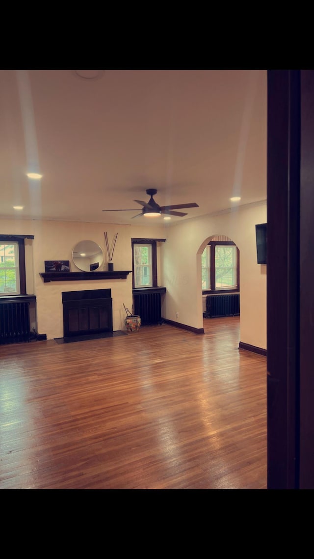 1065 Sunbury Rd, Columbus, OH 43219 - unfurnished living room with a fireplace with flush hearth, wood finished floors, healthy amount of natural light, and radiator