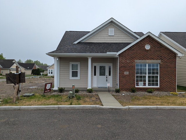 view of front of house with roof with shingles and brick siding