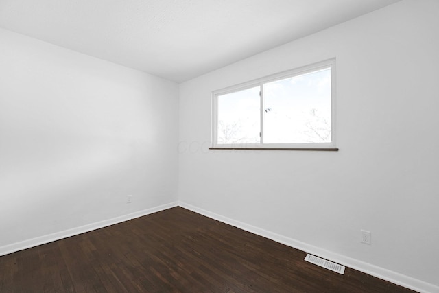 spare room with baseboards and dark wood-style floors