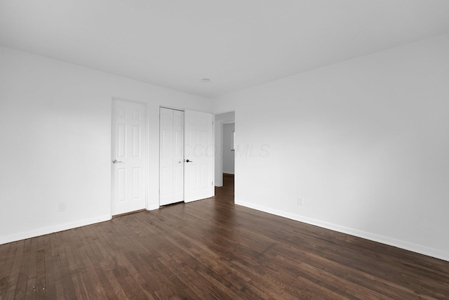 unfurnished bedroom featuring baseboards, dark wood-style flooring, and a closet