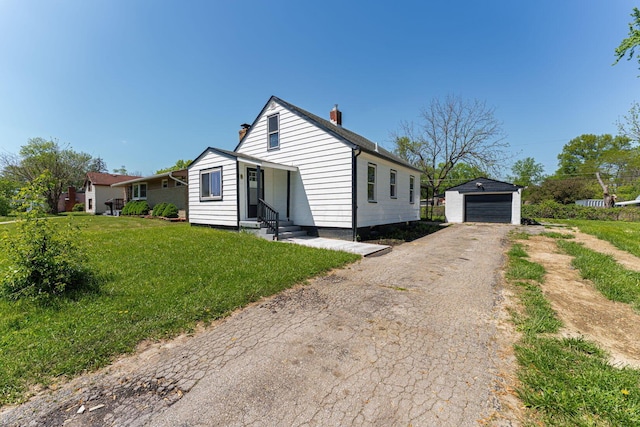 view of front of house featuring an outbuilding, a detached garage, a chimney, entry steps, and a front lawn