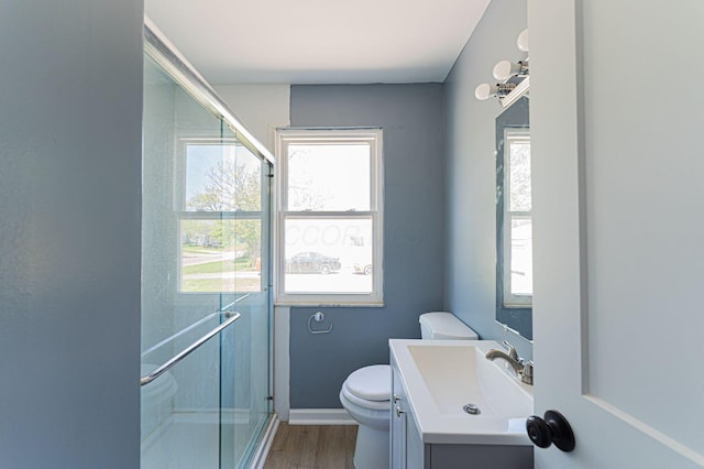full bathroom with a shower stall, toilet, wood finished floors, vanity, and baseboards