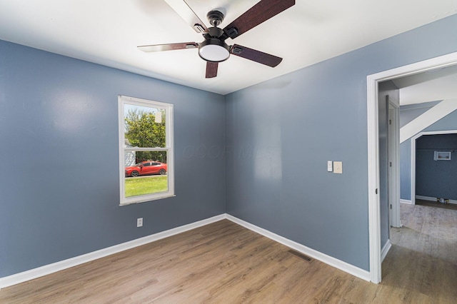spare room featuring wood finished floors, a ceiling fan, and baseboards