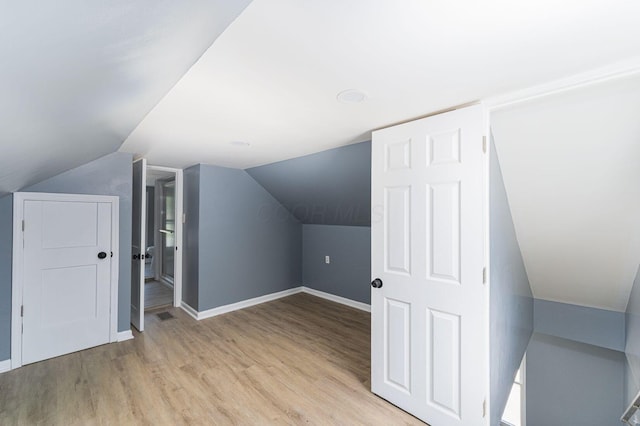 bonus room featuring light wood-style flooring, baseboards, and vaulted ceiling