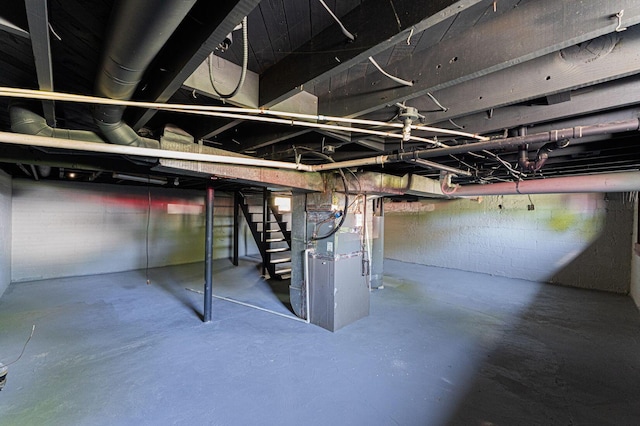 unfinished below grade area featuring stairway and heating unit