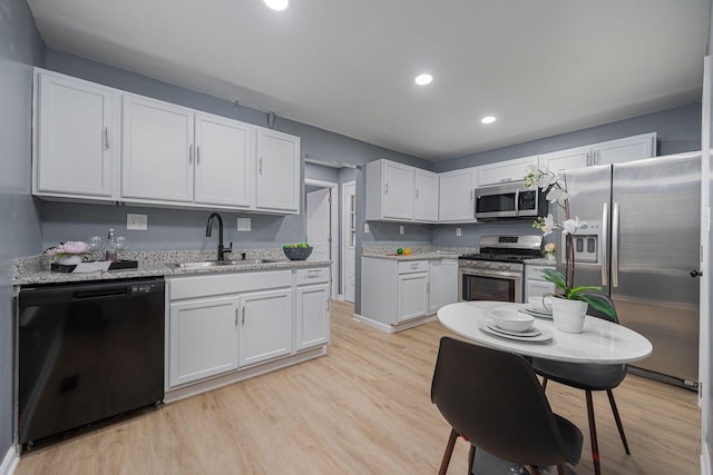 1828 Ferris Rd, Columbus, OH 43224 - kitchen featuring appliances with stainless steel finishes, white cabinets, light wood-style floors, recessed lighting, and light stone countertops
