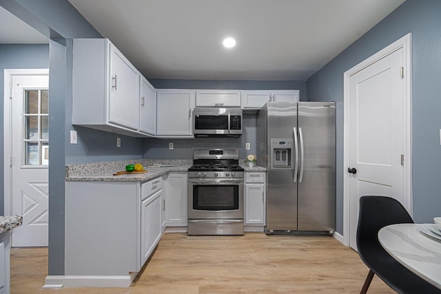 1828 Ferris Rd, Columbus, OH 43224 - kitchen with appliances with stainless steel finishes, white cabinets, light wood-style flooring, recessed lighting, and light stone countertops
