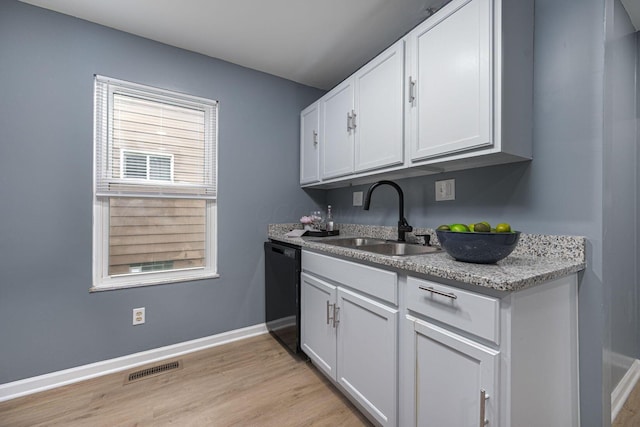 1828 Ferris Rd, Columbus, OH 43224 - kitchen with black dishwasher, white cabinetry, light wood-style floors, and light stone countertops