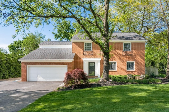 view of front of home featuring a garage, driveway, a front yard, and brick siding