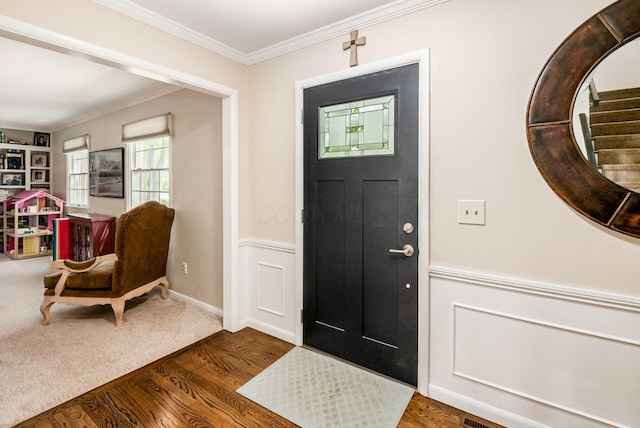 foyer featuring ornamental molding, wood finished floors, and a wainscoted wall