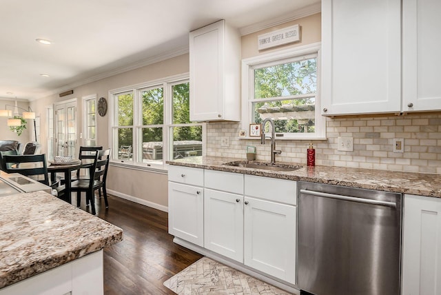 kitchen with stainless steel dishwasher, a sink, healthy amount of natural light, ornamental molding, and dark wood finished floors