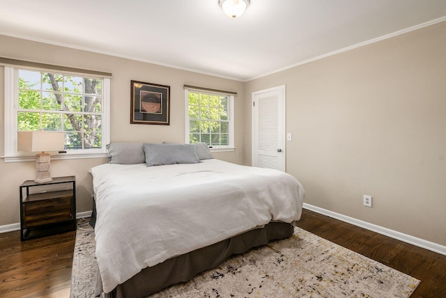bedroom with baseboards, dark wood-style floors, crown molding, and a closet