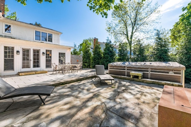 view of patio / terrace featuring french doors, outdoor dining space, and a covered hot tub