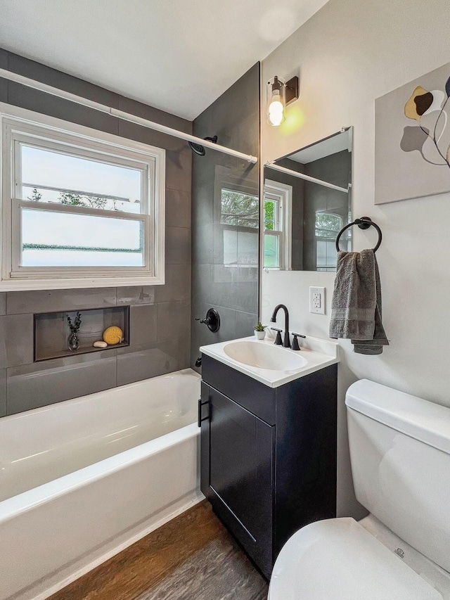 bathroom with toilet, wood finished floors, vanity, and shower / tub combination