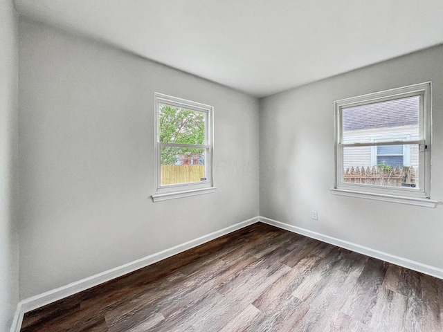 spare room with dark wood-type flooring and baseboards