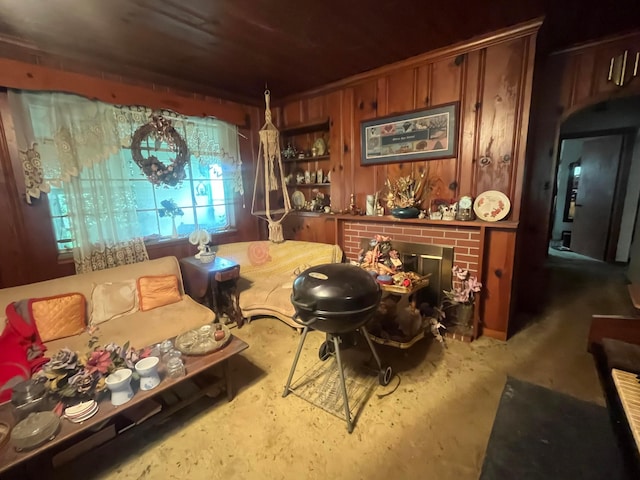 living area featuring a brick fireplace and unfinished concrete flooring