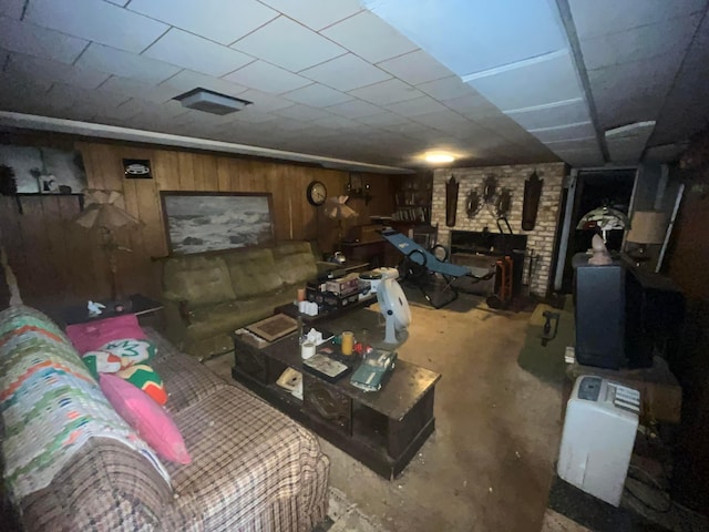 living area featuring a fireplace, wood walls, and concrete floors