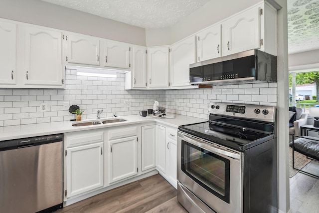 407 Yarmouth Ln, Columbus, OH 43228 - kitchen featuring stainless steel appliances, a sink, a textured ceiling, wood finished floors, and white cabinetry