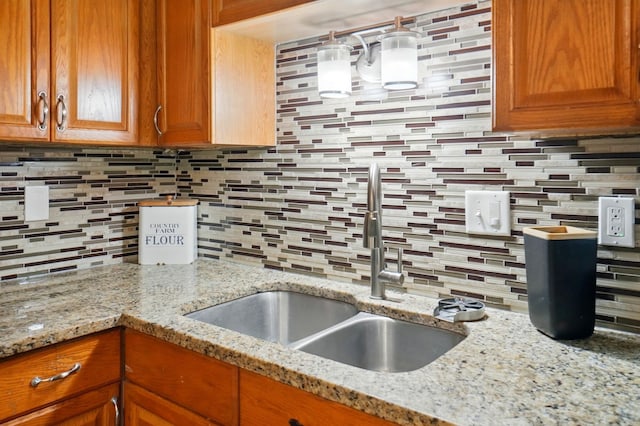 135 N Creekview Ct, Baltimore, OH 43105 - kitchen with backsplash, a sink, brown cabinets, and light stone counters