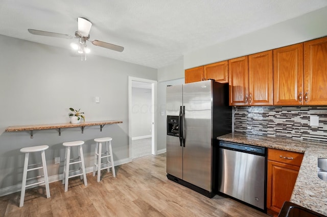 135 N Creekview Ct, Baltimore, OH 43105 - kitchen with stainless steel appliances, brown cabinets, decorative backsplash, and a breakfast bar area