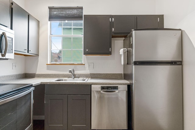 kitchen with stainless steel appliances, a sink, and light countertops