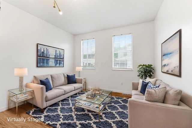 living area with wood finished floors, baseboards, and lofted ceiling