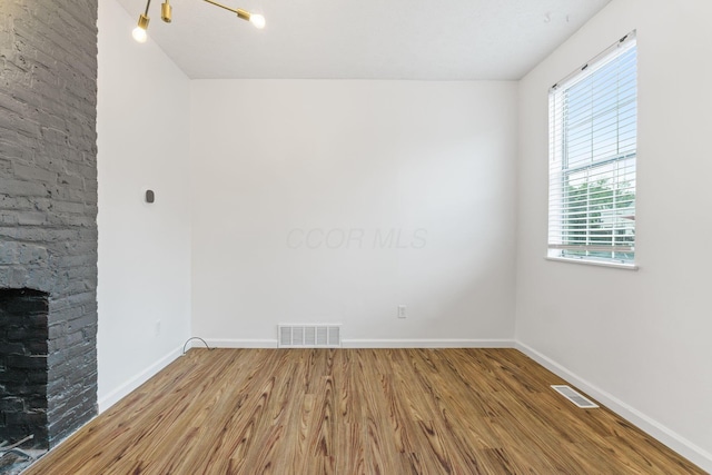 empty room with wood finished floors, healthy amount of natural light, and baseboards
