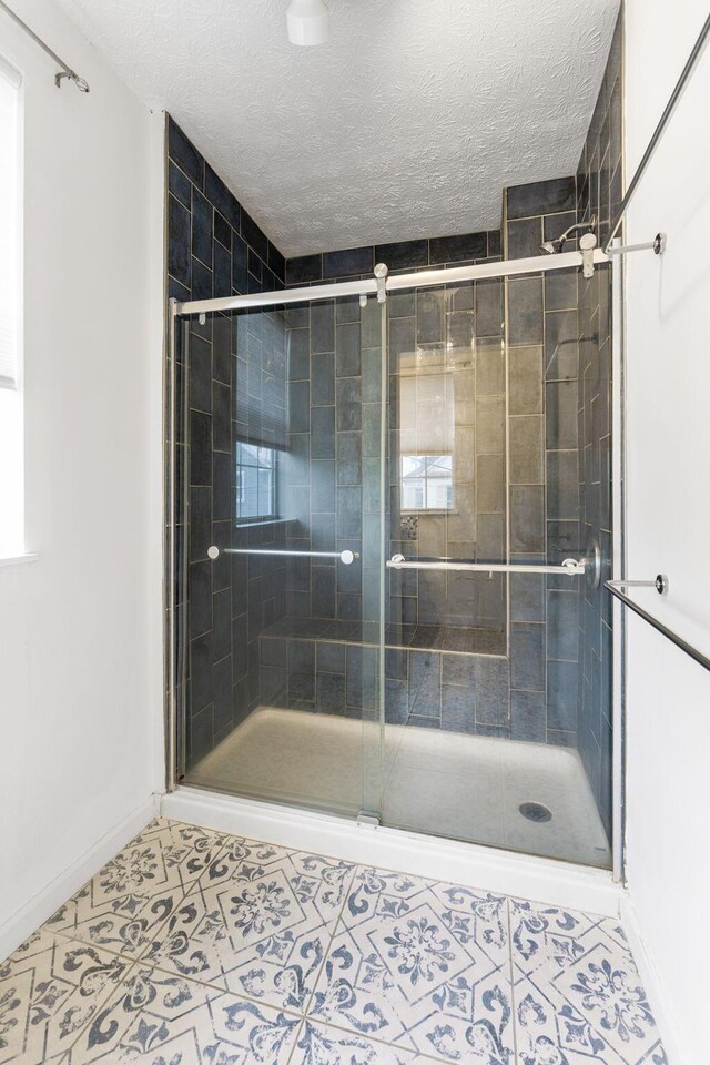 bathroom featuring baseboards, a stall shower, tile patterned flooring, and a textured ceiling