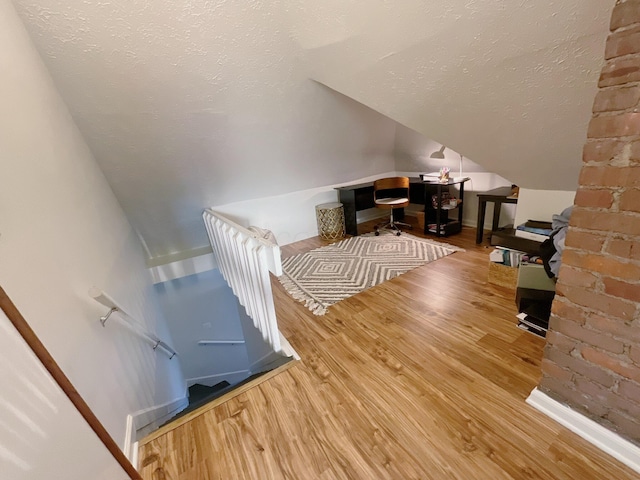 additional living space with wood finished floors, vaulted ceiling, and baseboards