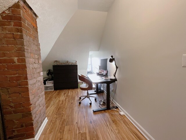 office area with wood finished floors, vaulted ceiling, and baseboards
