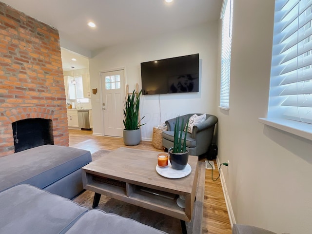 living area featuring light wood-style flooring, baseboards, a fireplace, and recessed lighting