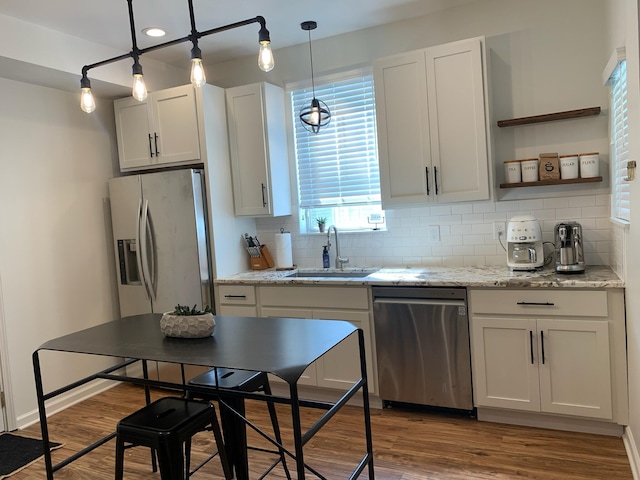 kitchen with stainless steel appliances, a sink, tasteful backsplash, and wood finished floors