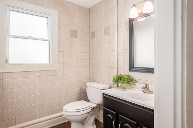 half bath featuring tile walls, toilet, and vanity