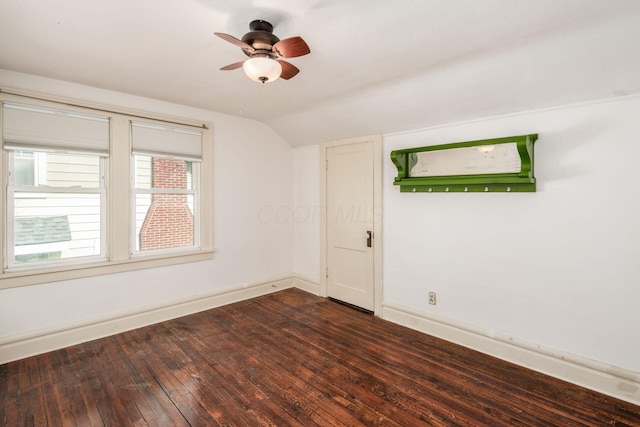 empty room featuring lofted ceiling, baseboards, a ceiling fan, and dark wood-style floors