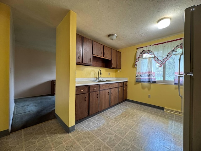 3457 Petzinger Rd, Columbus, OH 43232 - kitchen with a sink, light countertops, freestanding refrigerator, baseboards, and a textured ceiling
