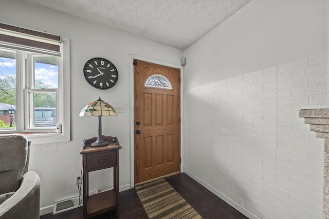 foyer entrance with dark wood finished floors, a textured ceiling, and baseboards