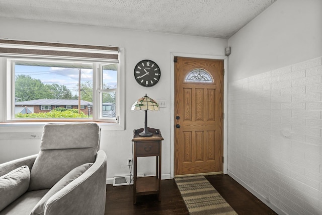 foyer with dark wood-style floors, a textured ceiling, and baseboards