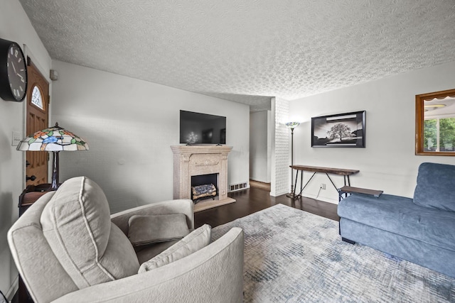 living room with wood finished floors, a fireplace, a textured ceiling, and baseboards