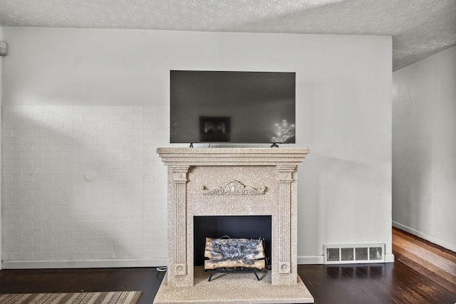 detailed view of wood finished floors, a textured ceiling, a fireplace, and baseboards