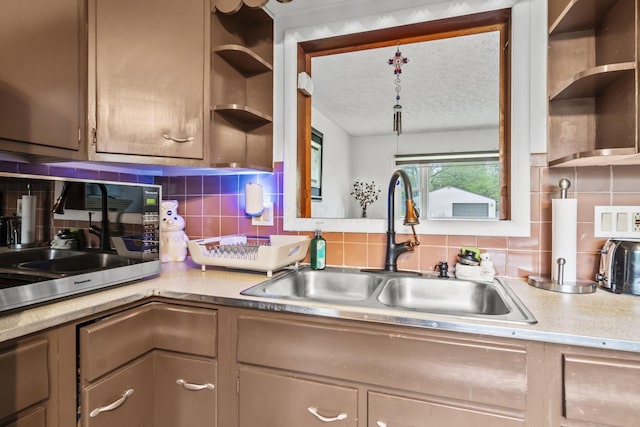 kitchen with open shelves, a sink, light countertops, and decorative backsplash