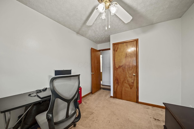 office featuring light colored carpet, ceiling fan, a textured ceiling, and baseboards