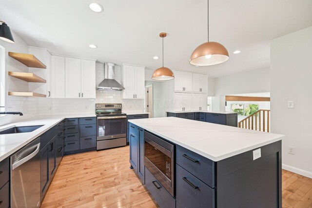 500 Cherrington Ct, Westerville, OH 43081 - kitchen featuring stainless steel appliances, wall chimney exhaust hood, a sink, a kitchen island, and light wood-style flooring