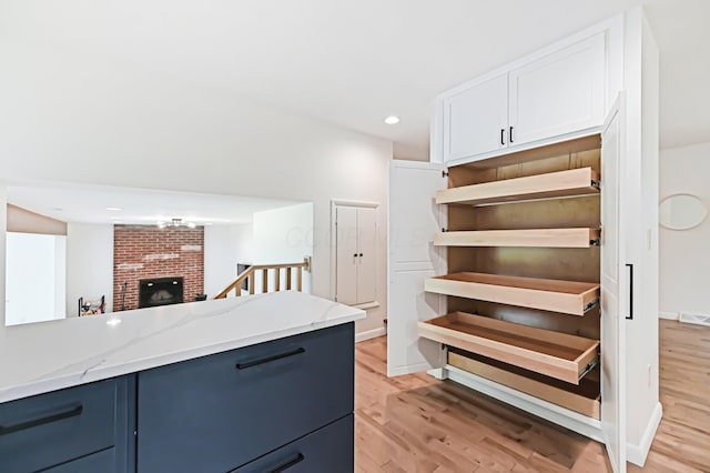 500 Cherrington Ct, Westerville, OH 43081 - kitchen featuring light wood-type flooring, blue cabinets, light stone countertops, recessed lighting, and a brick fireplace