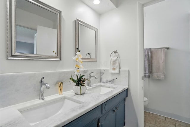 5508 Aspen Rd, Columbus, OH 43229 - full bathroom with toilet, baseboards, double vanity, and stone finish floors