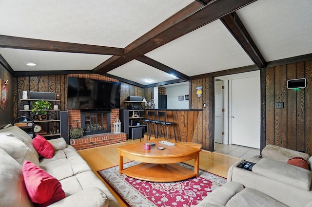 5508 Aspen Rd, Columbus, OH 43229 - living room featuring wood walls, beamed ceiling, wood finished floors, and a brick fireplace