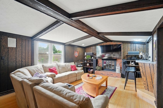 5508 Aspen Rd, Columbus, OH 43229 - living room with hardwood / wood-style floors, wood walls, beam ceiling, a textured ceiling, and a fireplace